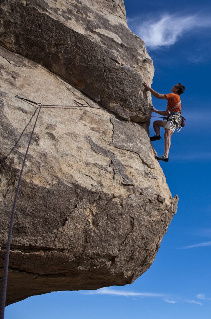 Climber ascends a steep, rock overhang in J Tree California