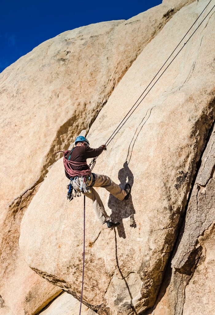 A man rappels down a climbing route on Intersection Rock, the birthplace of climbing in J Tree