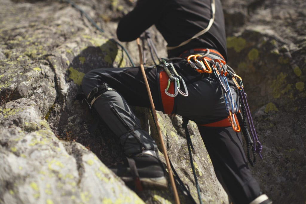 Man rock climbing with a stick clip pole on the harness