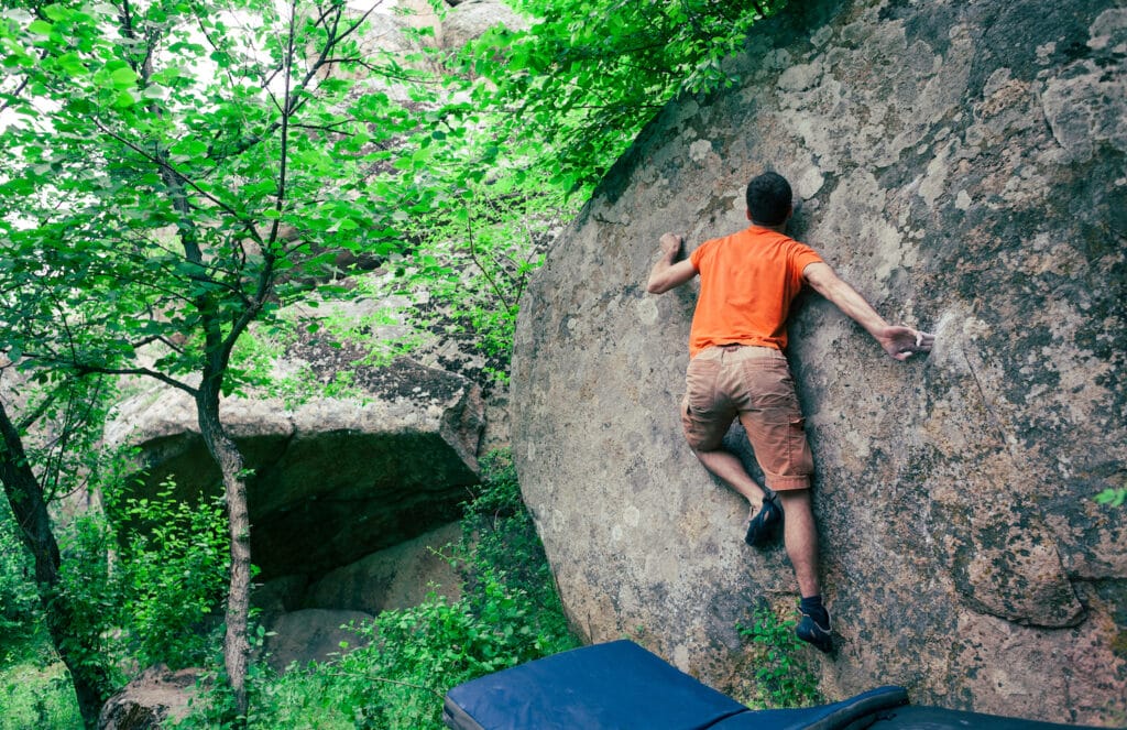 athlete shifting body weight on boulder