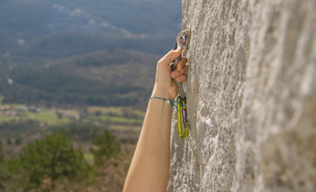 female climber clipping bolt