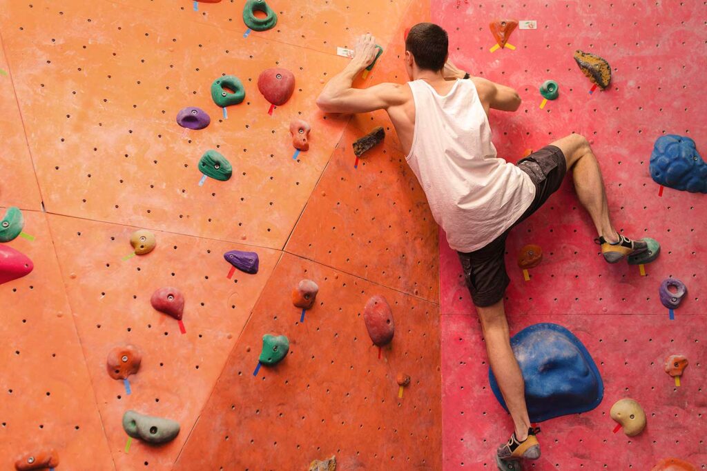 climber on a climbing wall in bouldering gym with la sportiva shoes