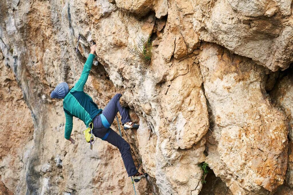 young woman rock climbing outdoors with La Sportiva climbing shoes
