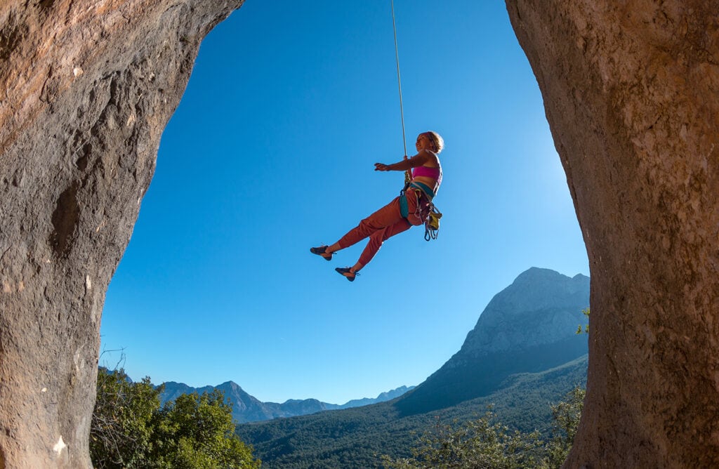 A girl hanging with a belay after ascending a climb without prior knowledge. She has a chalk bag.