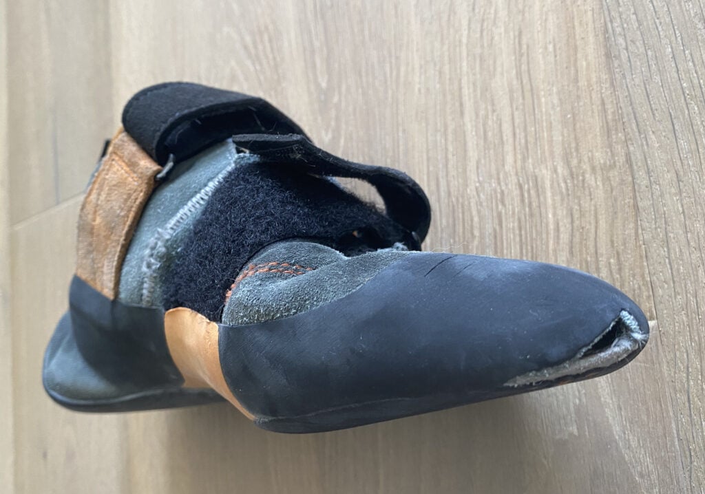 severely damaged climbing shoes with large tear in the toe box - a good example of when to replace climbing shoes