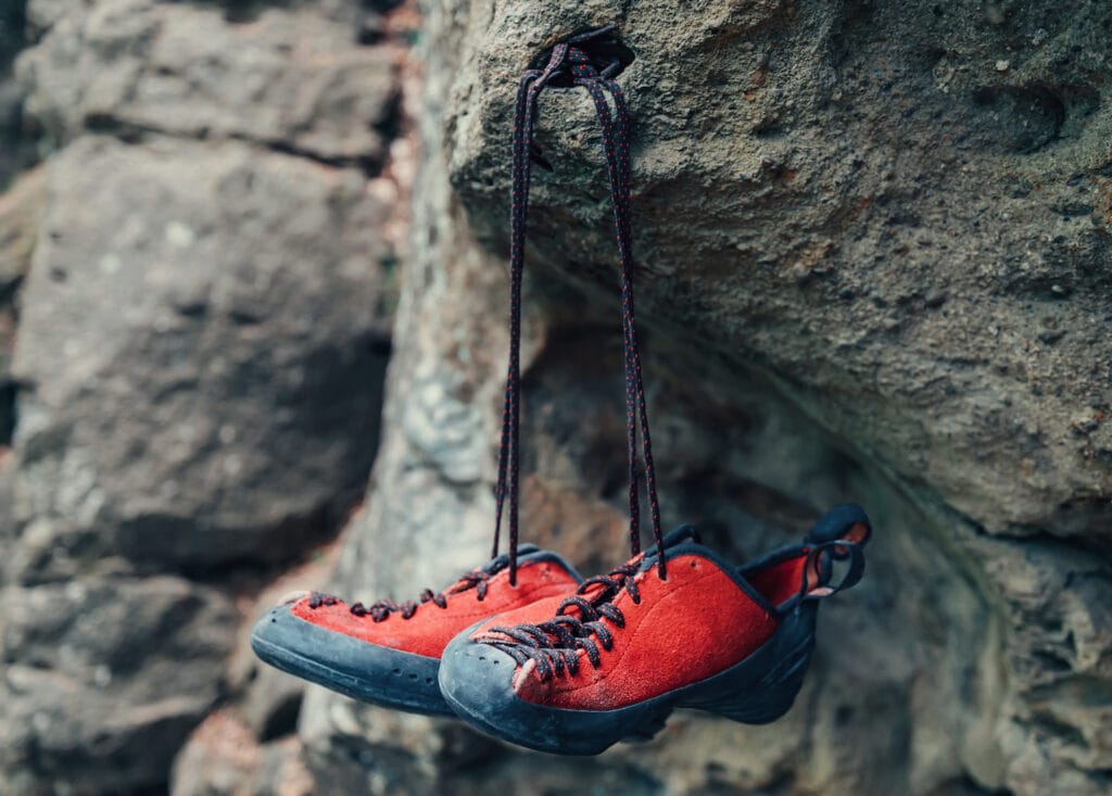 red lace climbing shoes hanging from a rock