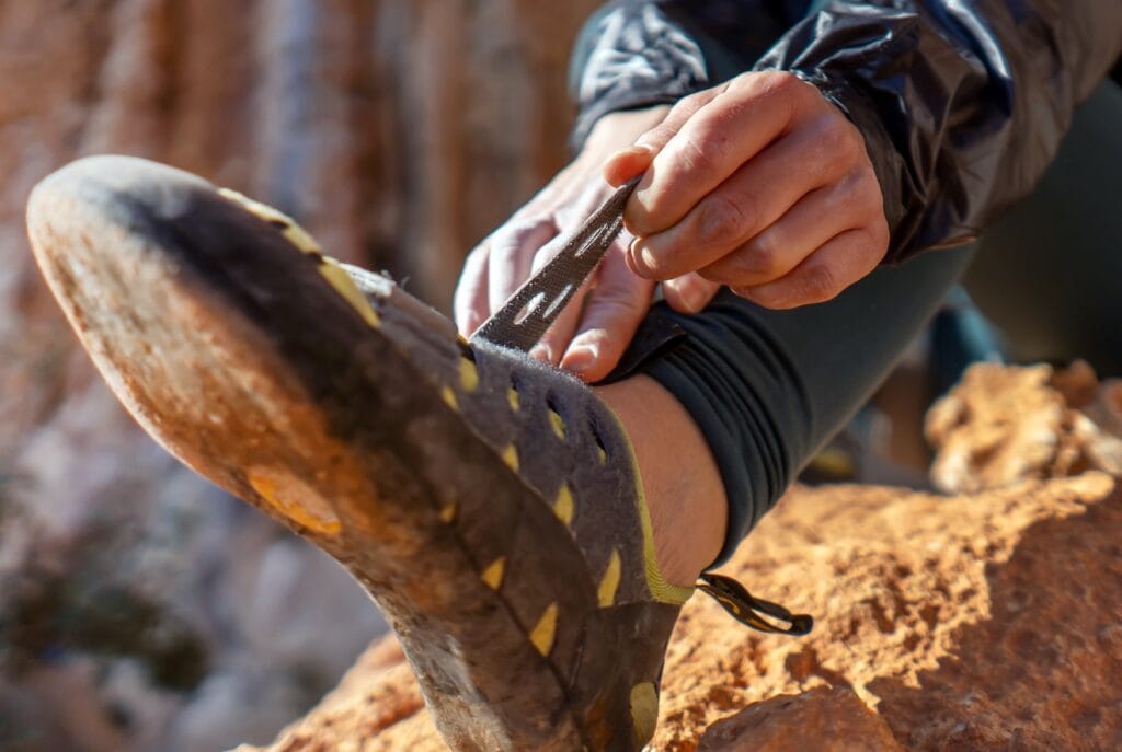 Rock climber putting on shoes. Beginner shoes tend to have a roomy toe box like here.