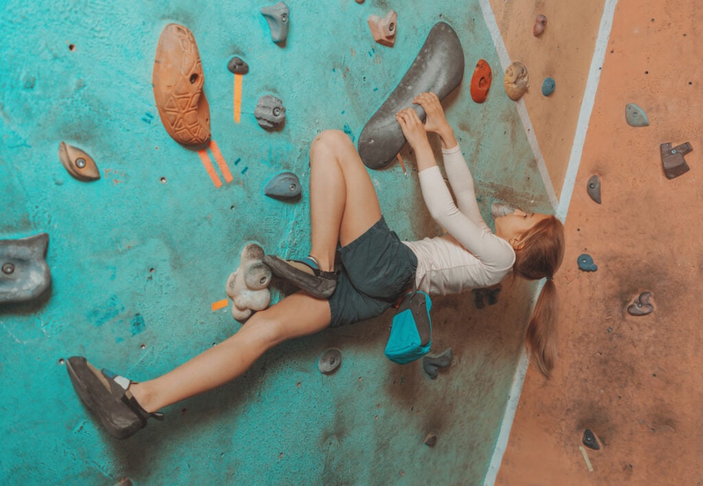 Female climber in the gym doing an outside flag