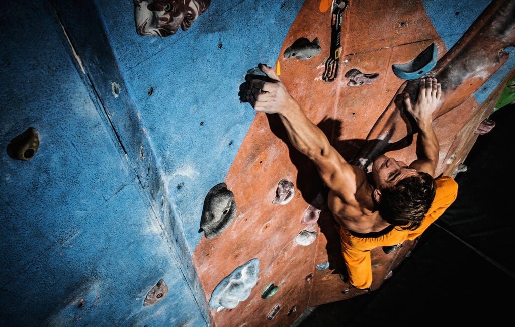 man practicing rock-climbing on a rock wall indoors