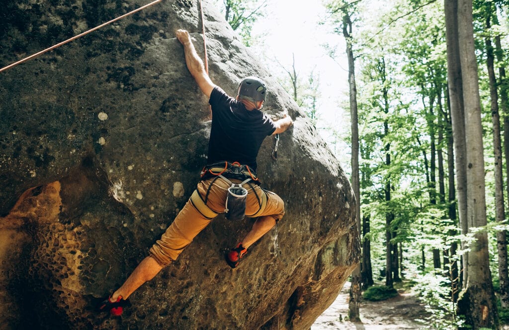 male rock climber climbing in pants