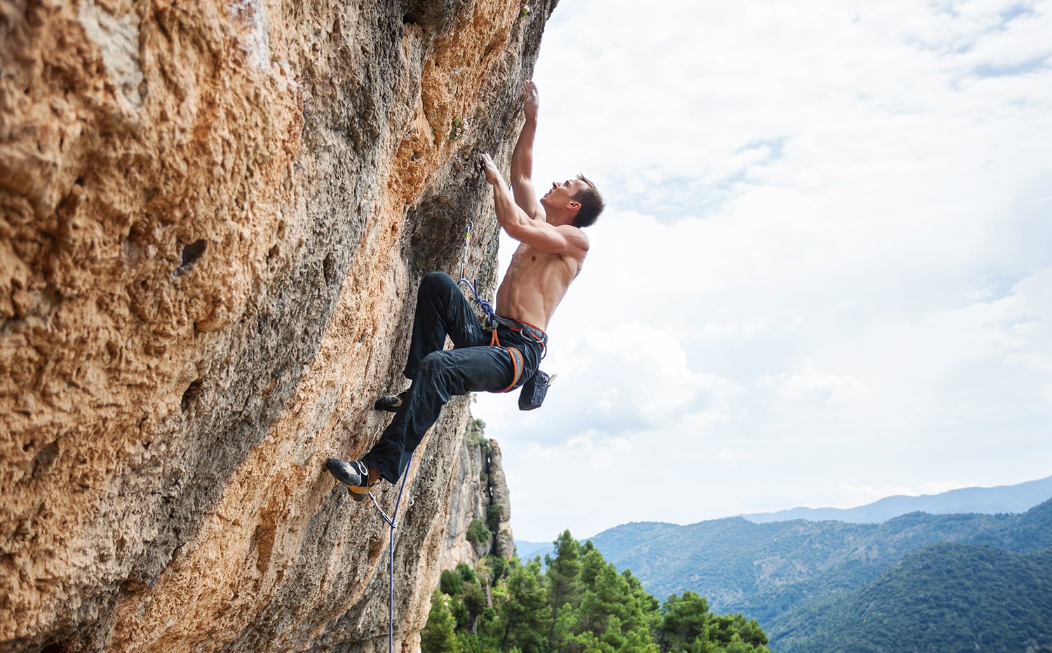 man rock climbing in jeans