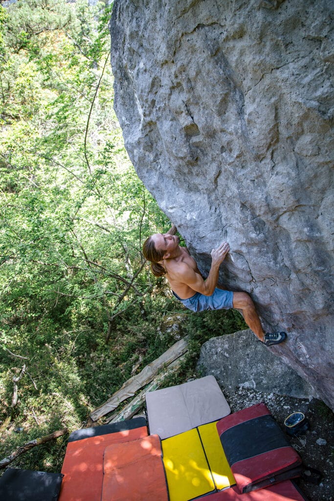 climber on a hard boulder problem using crash pad