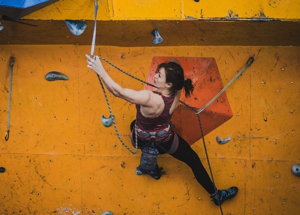 woman climbing in gym with climbing ropes