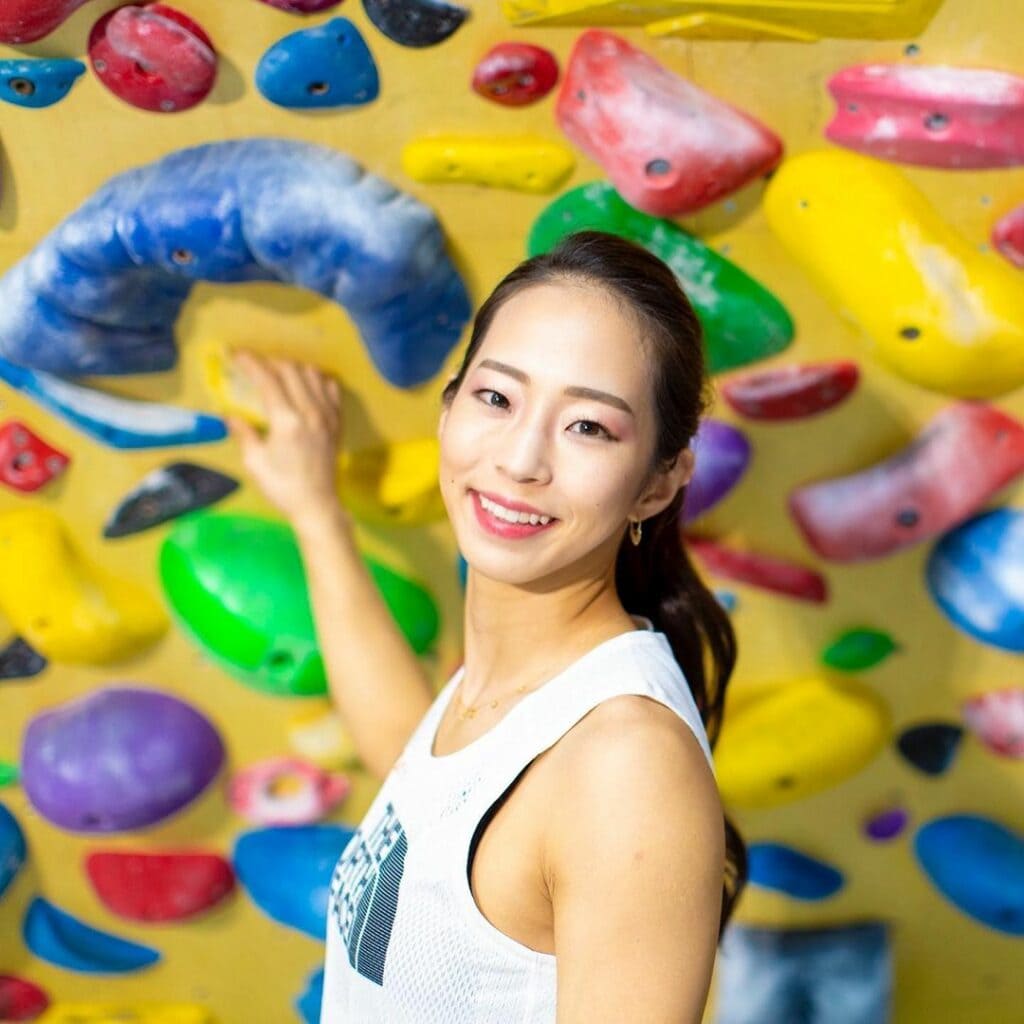 Akiyo Noguchi in front of an artificial boulder in the gym