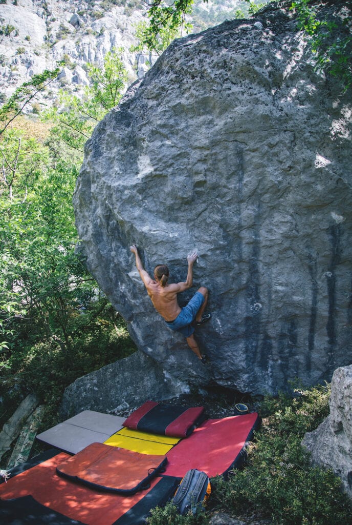 outdoor climber on a boulder with multiple pads for falls underneath