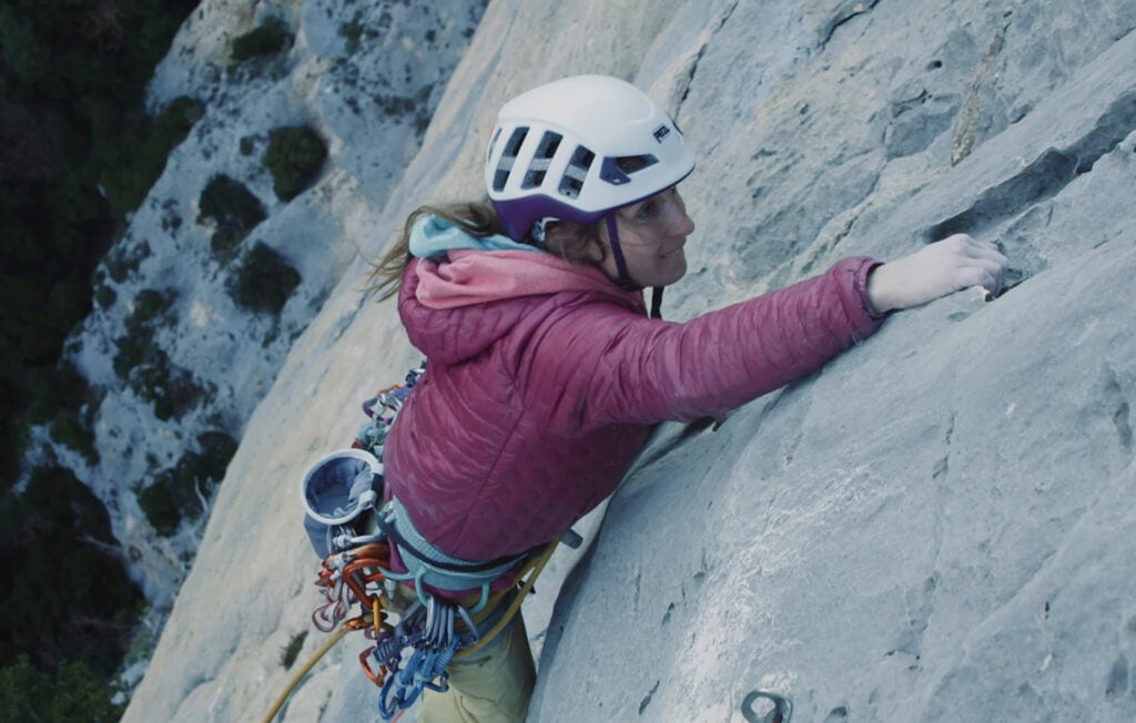 Female climber wearing Petzl Meteor multi-use helmet on a trad route