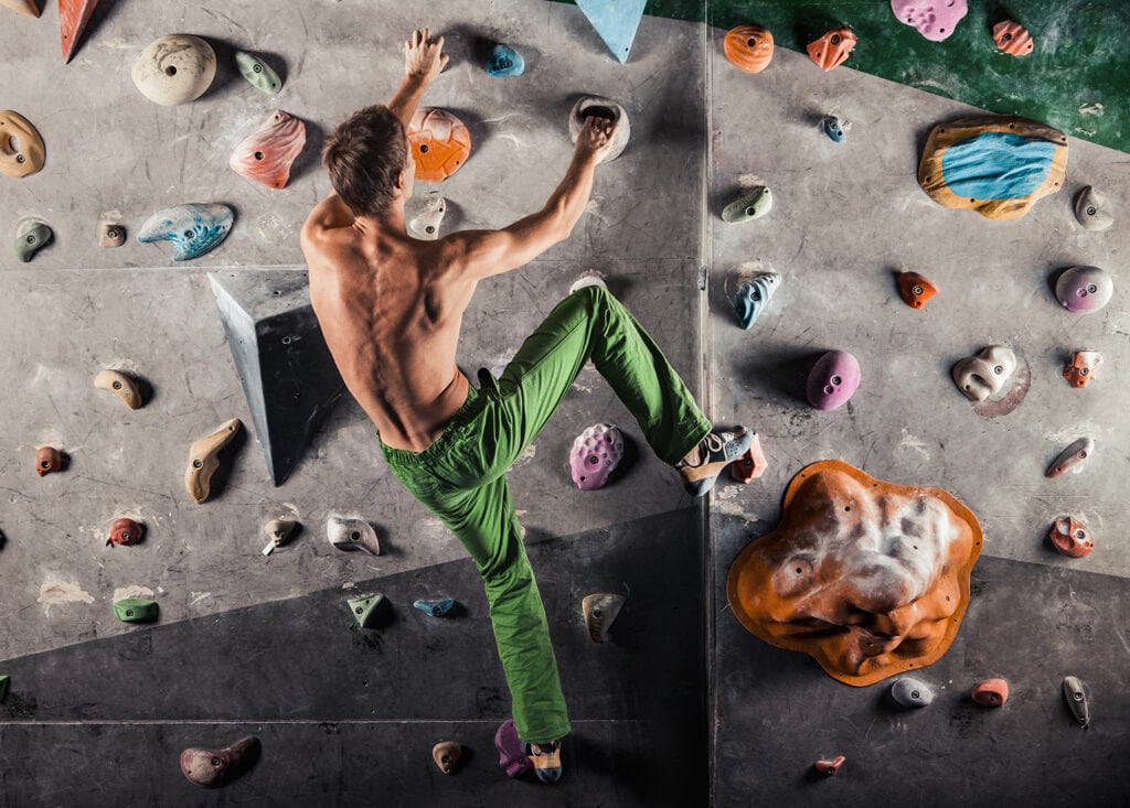 man climbing indoors on artificial wall
