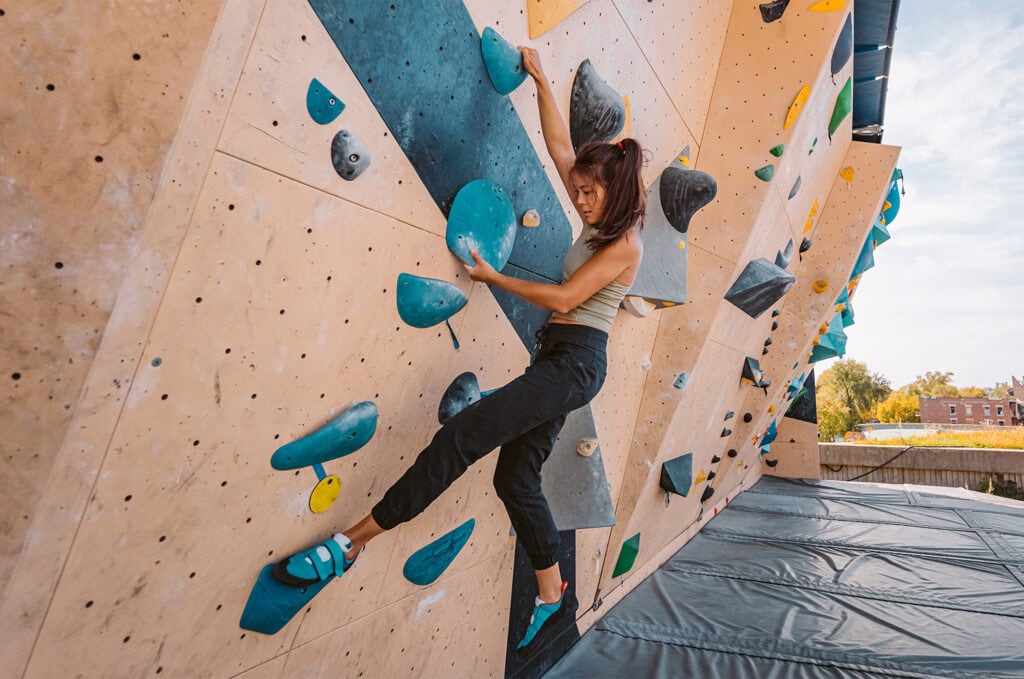 Female climber bouldering on an artificial outdoor wall at the gym
