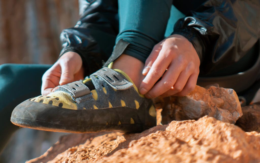 A young girl puts on special climbing shoes on her legs before climbing outdoor training