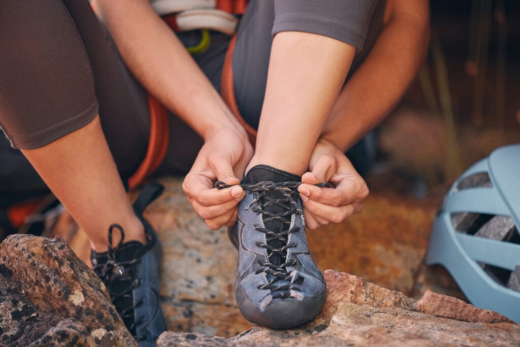 Woman tying her shoes in nature preparing for a rock climbing exercise