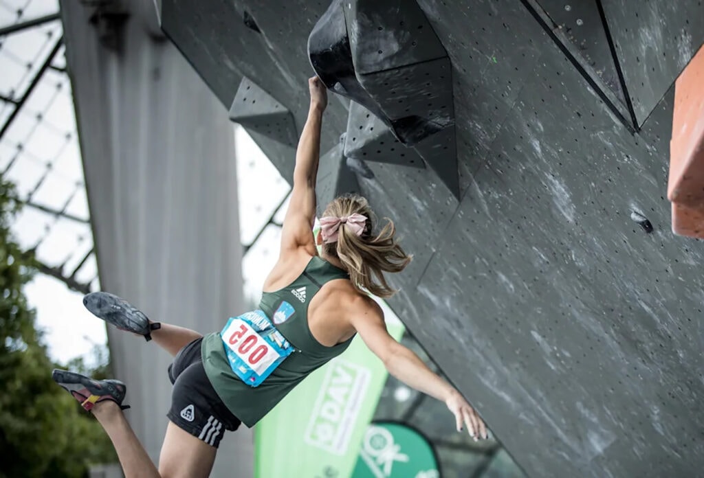 Climber Janja Garnbret in the woman's final. She hangs on to the bouldering high walls and swings in a dyno move