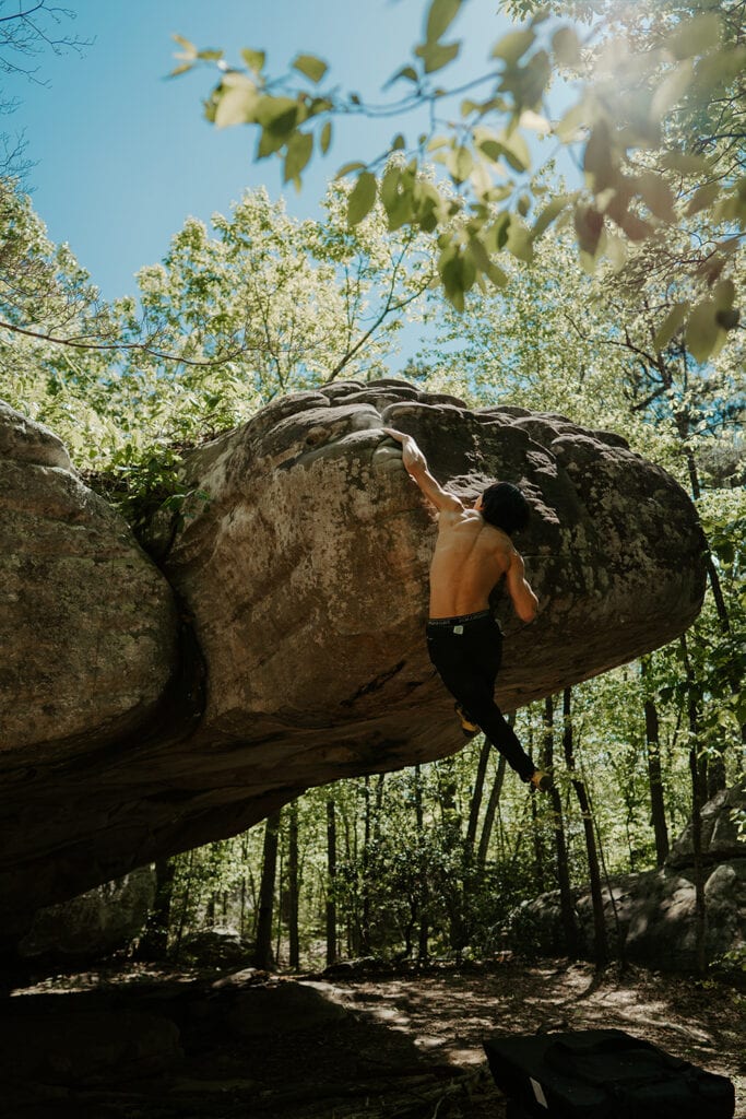 Athlete bouldering in nature