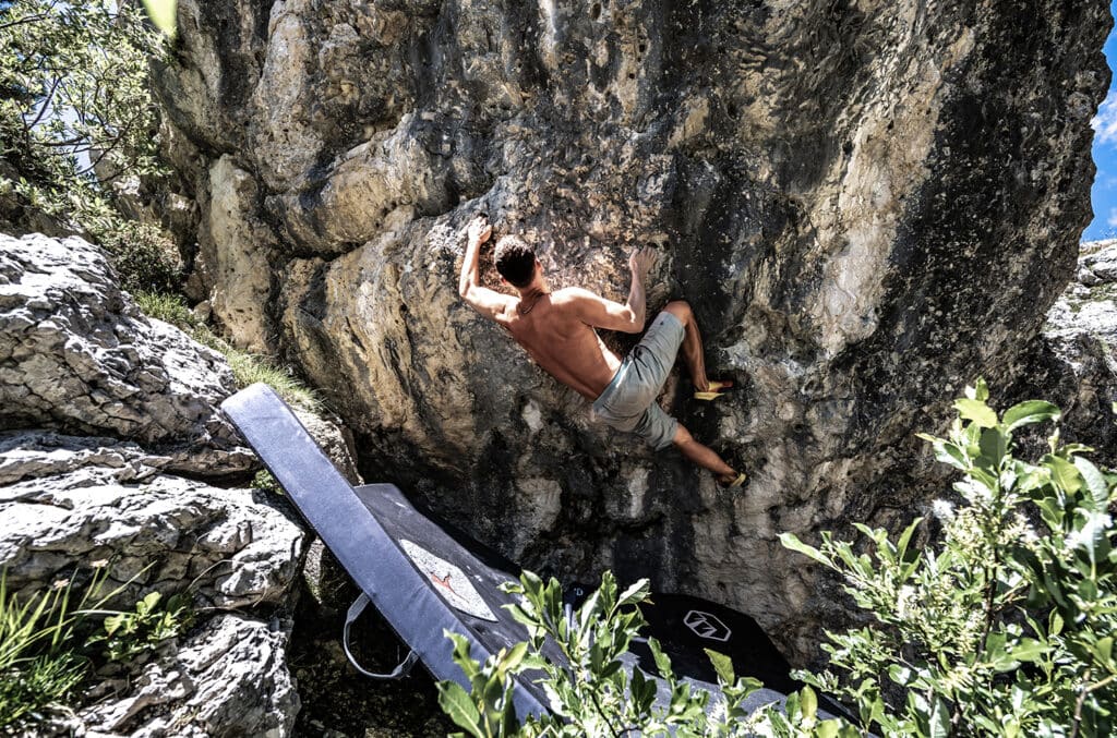 man bouldering outdoors with crash pads for protection