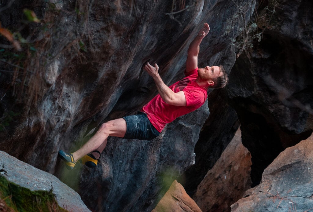 a man in red shirt is climbing up a rock formation outdoors