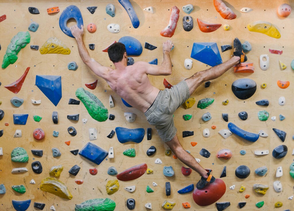 climber attempting a heel hook in th gym with slipper style shoes