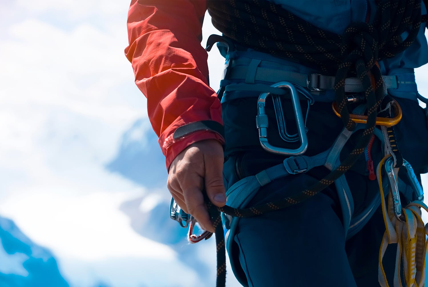 alpinist climbs to the top of a snowy mountain with climbing equipment, harness, carbines, rope
