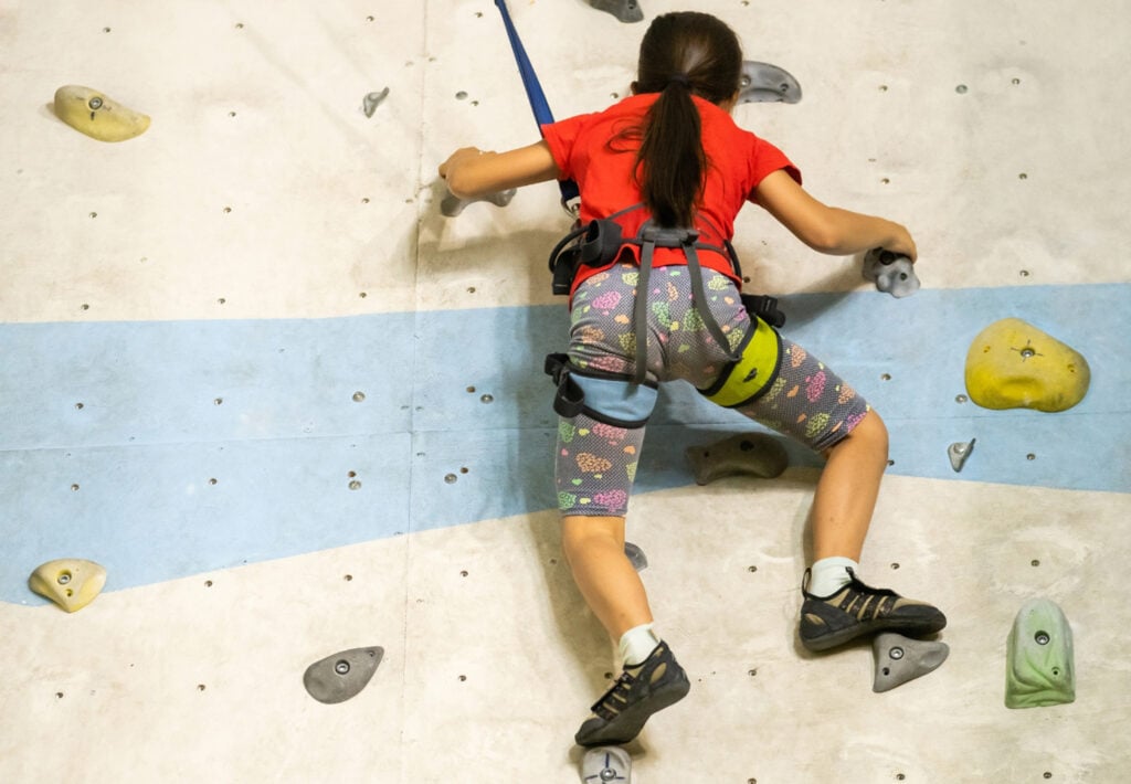 kid wearing climbing harness on an artificial wall (auto-belay)