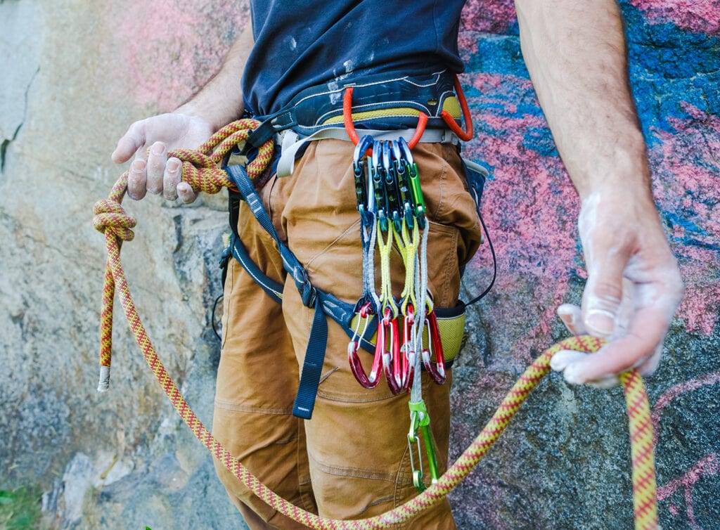 Rock climber with quickdraws on the harness gear loop and a carabiner to put on their belay loop