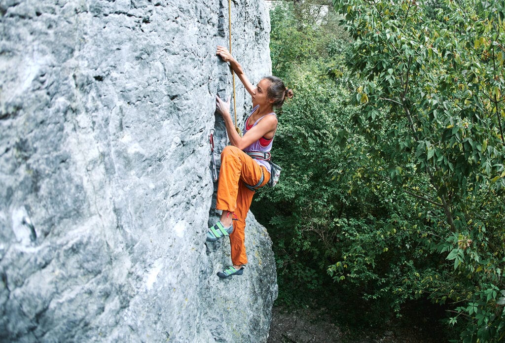 woman climber on top rope on a sport climbing route with cargo pants