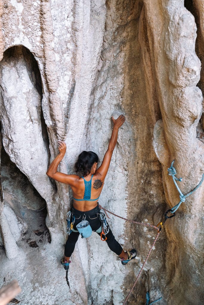 woman rock climbing outdoors using muscle strength to go up