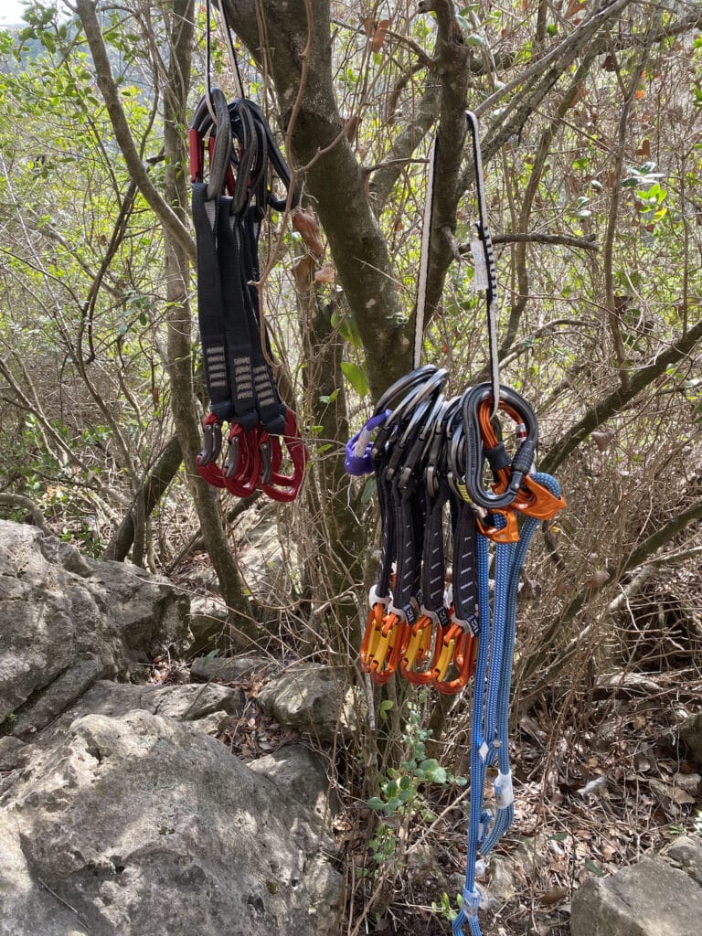 sport climbing gear at the crag with quickdraws, carabiners, cordelette and personal anchor