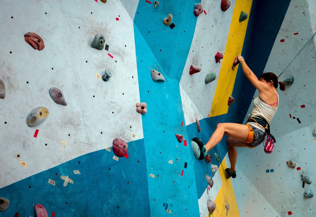 woman practicing gripping a climbing hold one of the gym's climbing routes