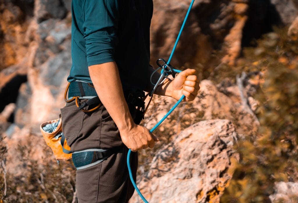 belayer being attentive to the climber's ascent (using a belay device, carabiner and waist harness)