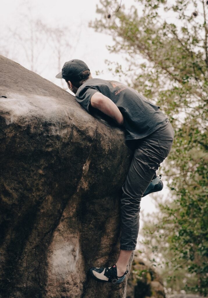 climber sending a boulder wearing a stylish cap and Tenaya shoes (cute bouldering outfit)