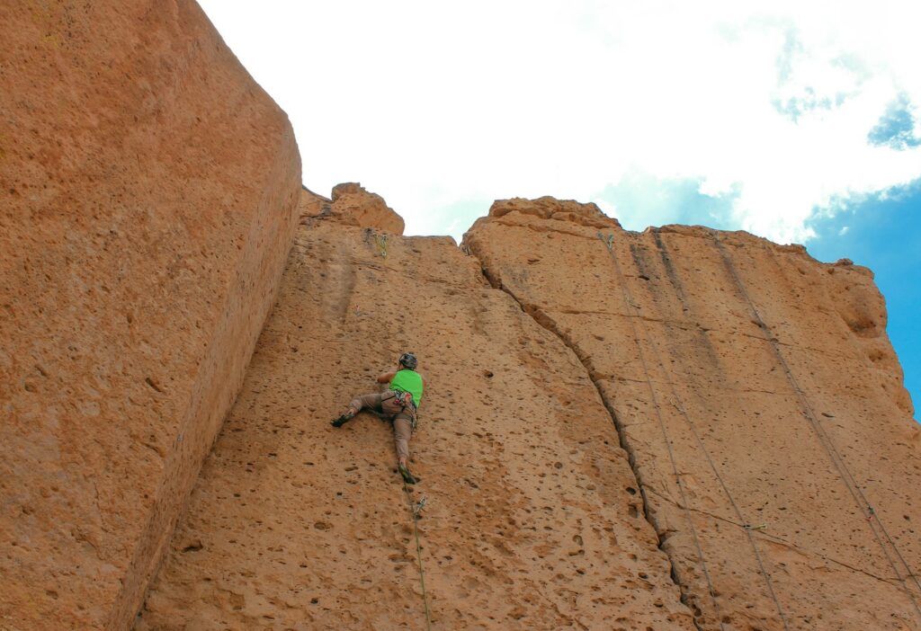 climber attempting to ascend on a relatively featureless rock face with only small pockets