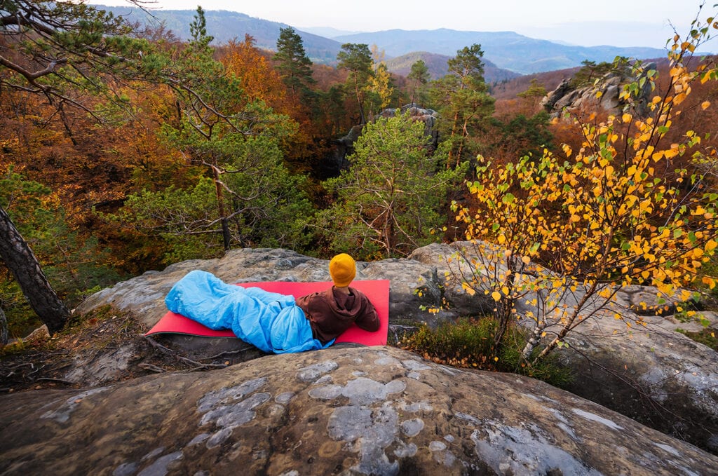 climber lies in the morning among the mountain landscape with rocks and trees