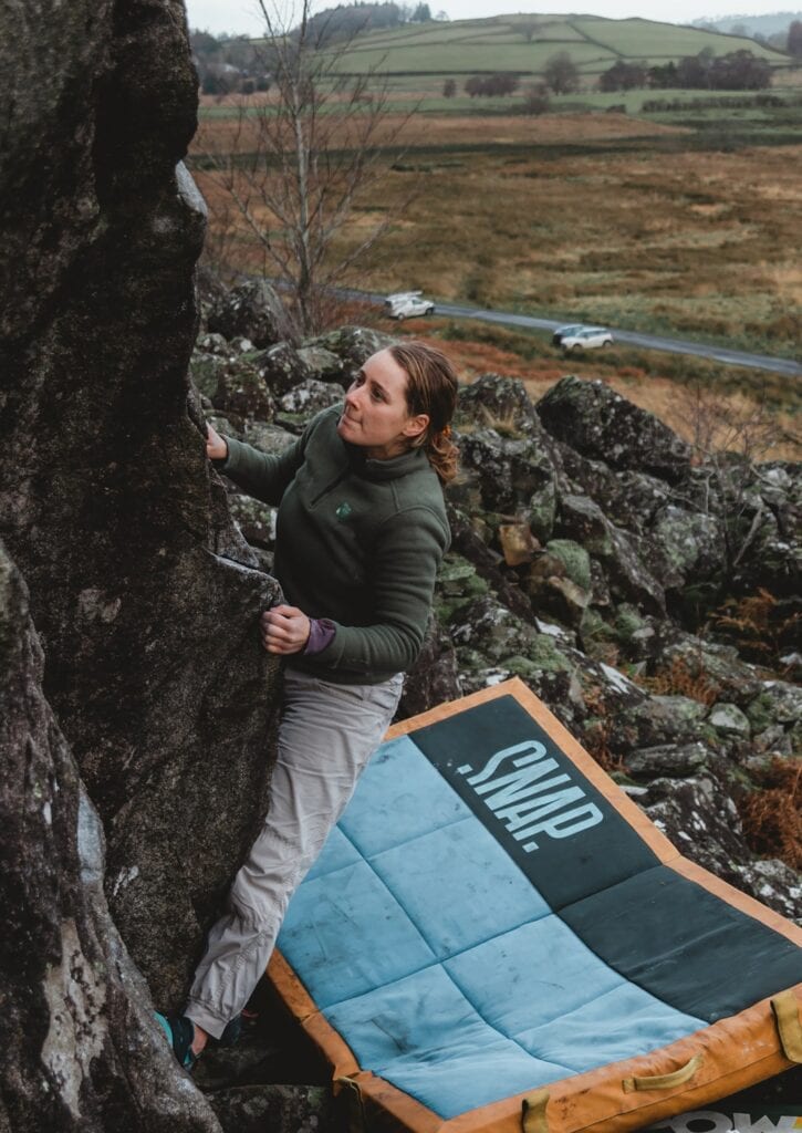 boulderer with a crash pad for protection
