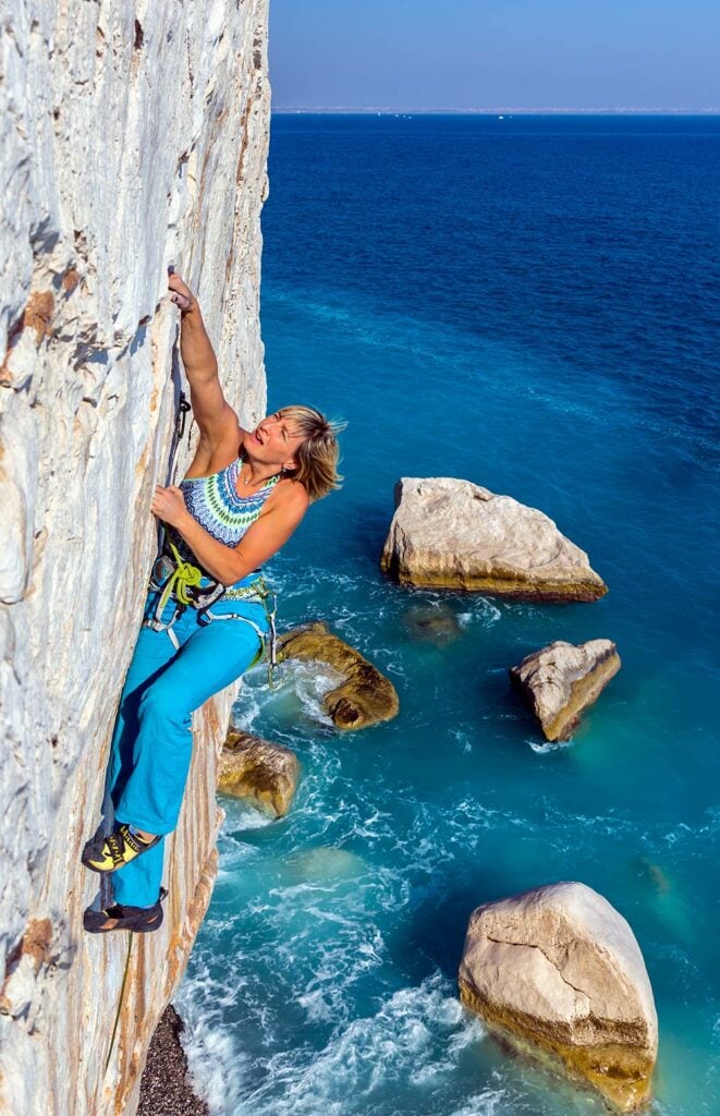 Woman summer climbing a cliff on the coast with new climbing pants (mountain hardwear) with zippered thigh pocket