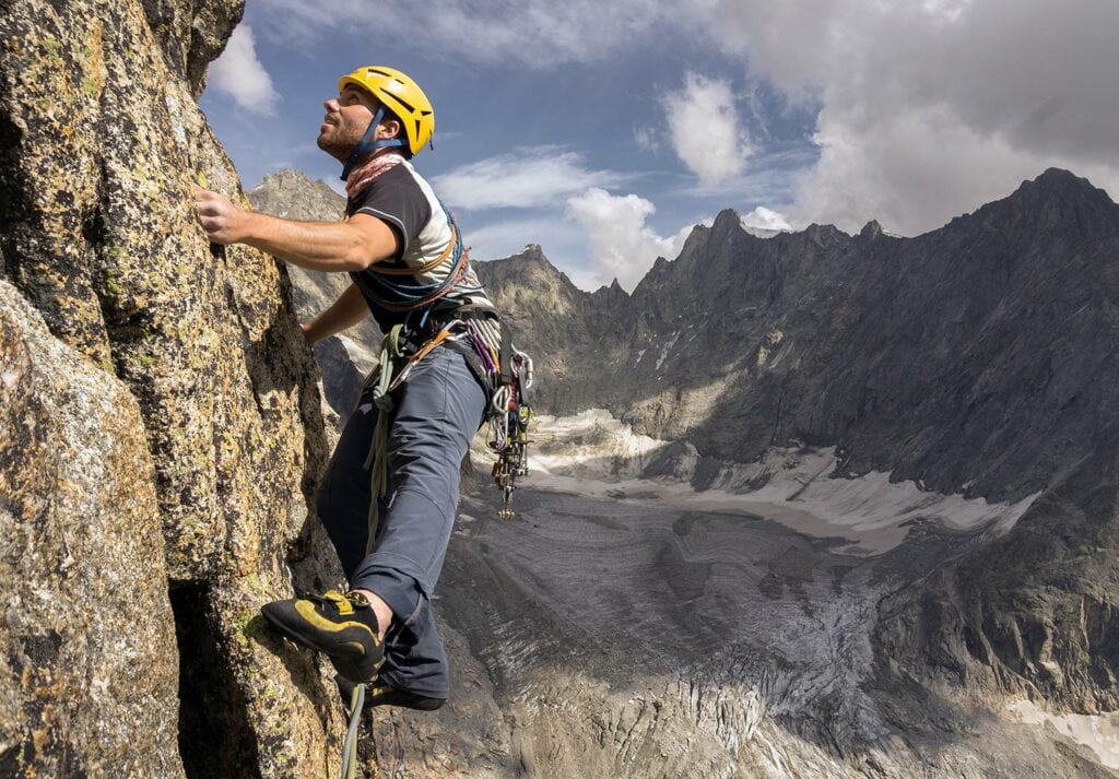 Climber climbing on a rock face on the italian side of Mont Blanc wearing the most durable climbing pants