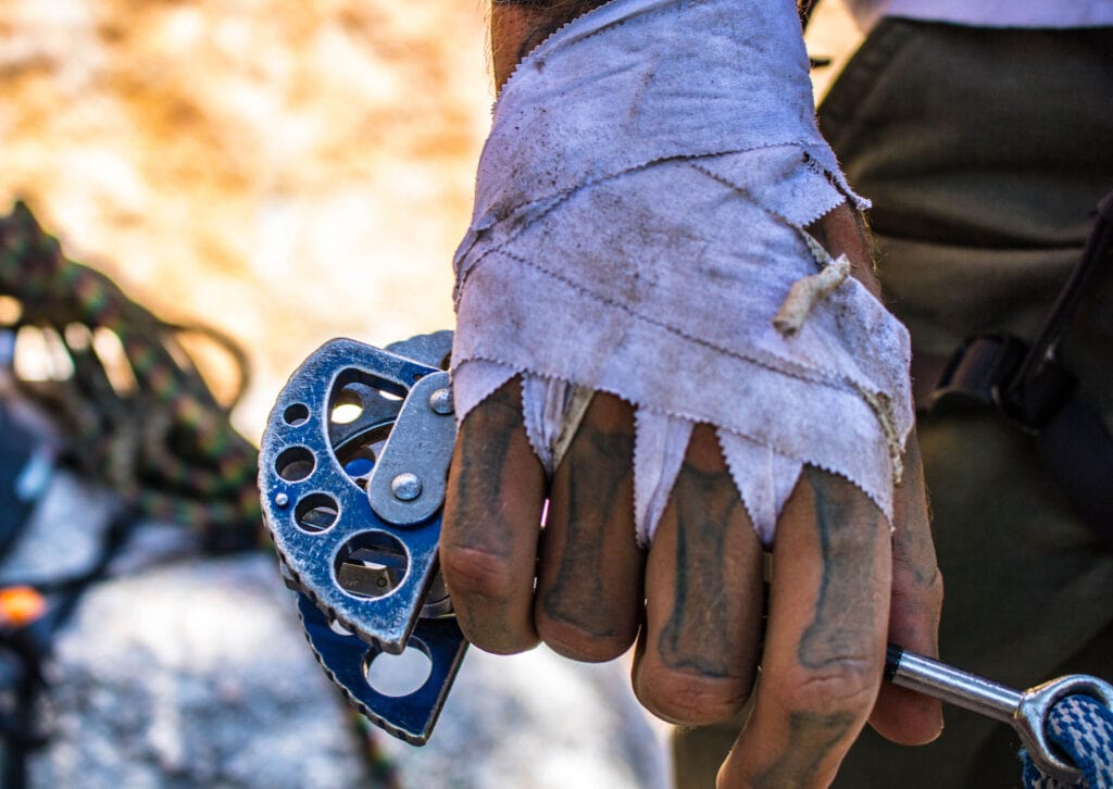 climber showing tapped hand holding a jamming device with expanding mechanisms (cam)