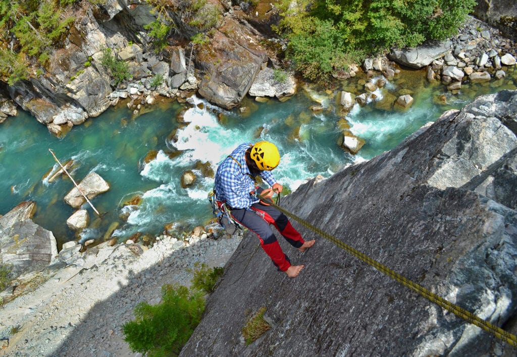 Young man rappels beautiful climbing route above the wild river