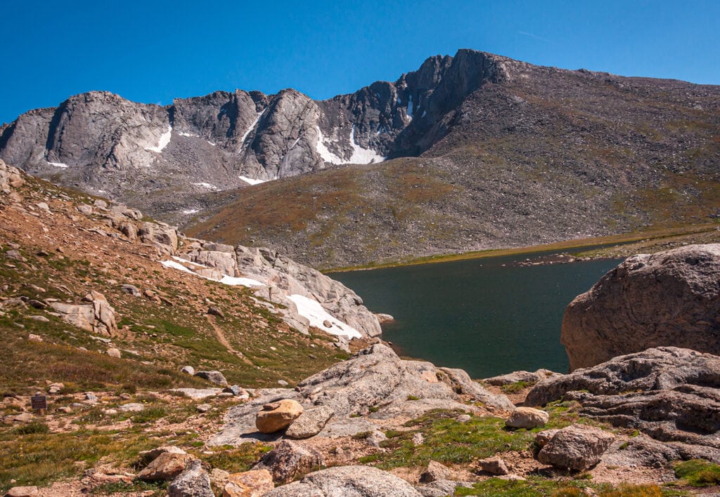 The rocky rugged shoreline of Summit Lake on Mount Evans, Colorado beneath a summer sky.
